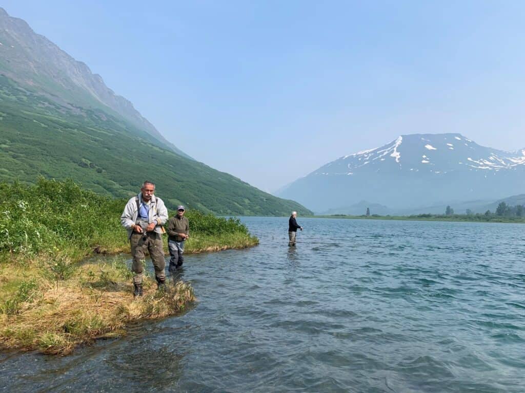 Secluded Kenai River with fishermen enjoying a peaceful day amidst scenic mountain views.