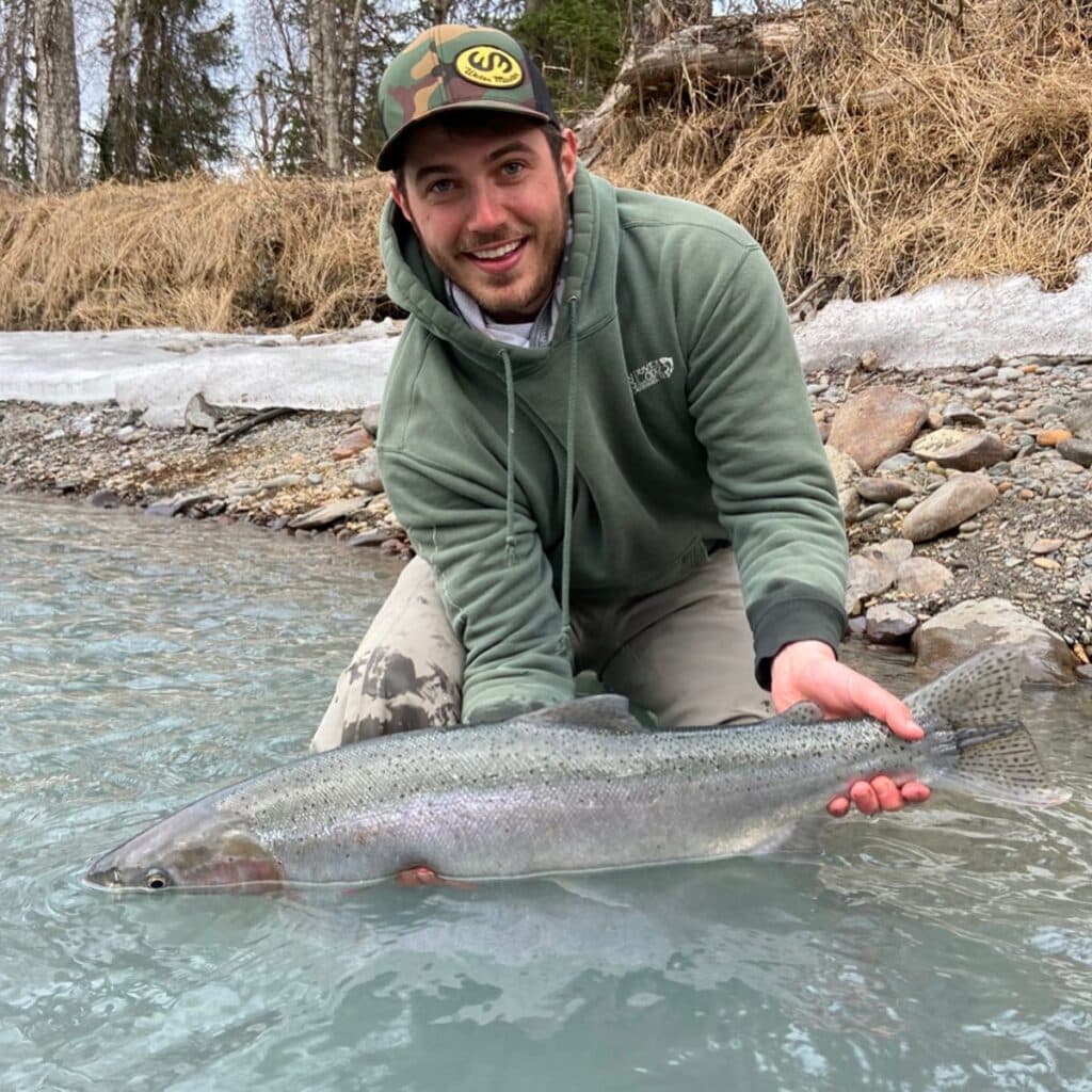 Rainbow trout caught in the Kenai River, Alaska, by a smiling angler during a fishing trip.