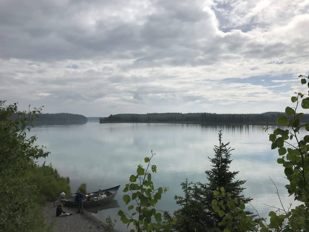 Serene river scene at Kenai River Drifters Lodge with calm waters and lush forest surroundings.