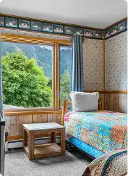 Kenai River Drifters Lodge interior with cozy bedroom and scenic mountain view.