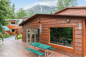Cozy wooden lodge on Kenai River with outdoor seating in Alaska.