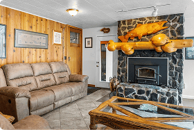 Cozy lodge living room with stone fireplace and wooden accents at Kenai River Drifters Lodge.
