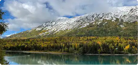Serene view of Kenai River with snow-capped mountains and lush forests in the background.