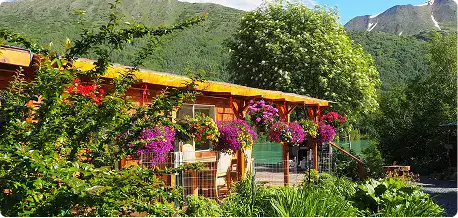 Charming lodge surrounded by lush green trees and colorful flowers in Kenai River area.