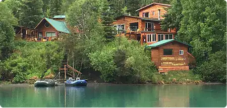 Remote lakeside lodges on the Kenai River in Alaska with lush greenery in the background.