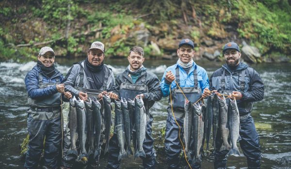 Fishing group holding fish on riverbank, Kenai River Drifters Lodge, Alaska.