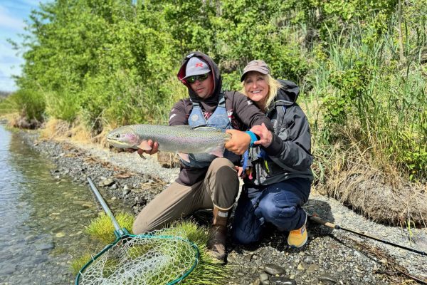 Guide with client holding rainbow trout on the Kenai River in June