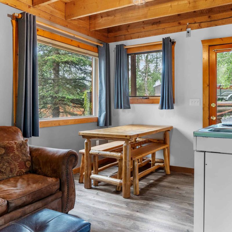 Cozy lodge interior with large windows, wooden accents, and rustic furniture, perfect for a relaxing Alaska getaway.