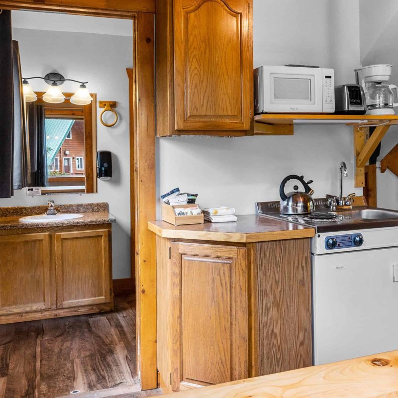 Cozy kitchenette with wood cabinets, microwave, and small appliances at Kenai River Drifters Lodge.