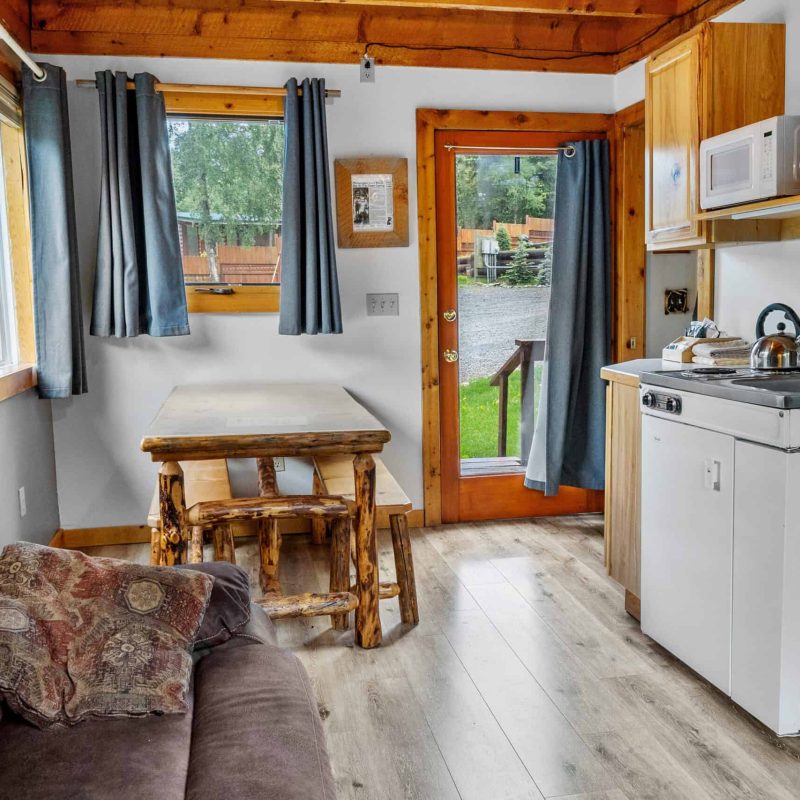Cozy cabin interior with wood accents and kitchen area at Kenai River Drifters Lodge, Alaska.