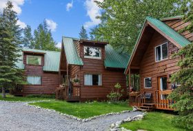 Cozy wooden cabins with green metal roofs surrounded by lush greenery at Kenai River Drifters Lodge.