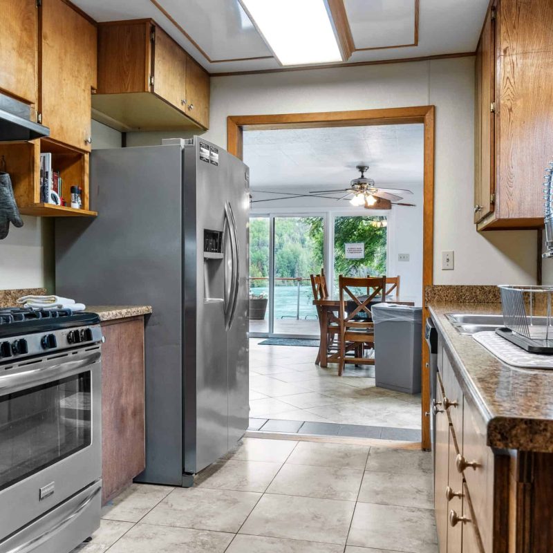 Stainless steel refrigerator in a cozy kitchen with wooden cabinets and modern appliances.