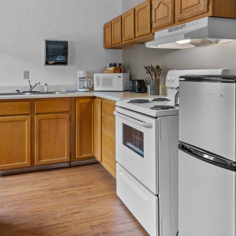 Cozy kitchen with wooden cabinets, white appliances, and modern amenities at Kenai River Drifters Lodge.