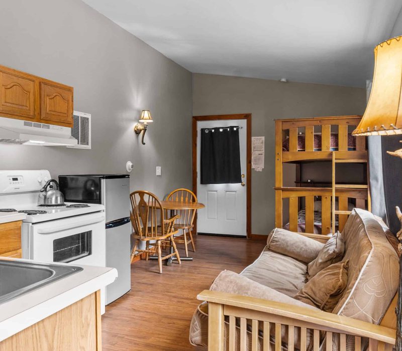 Cozy Kenai River Drifters Lodge interior with wooden furnishings and compact kitchen area.