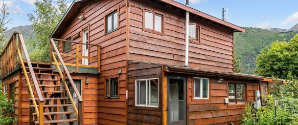 Rustic wooden lodge with stairs and mountain views at Kenai River Drifters Lodge.