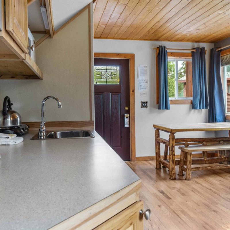 Cozy kitchen and dining area inside Kenai River Drifters Lodge with wooden accents and large windows.
